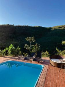 una piscina con sillas y una colina de fondo en Acqualume Cachoeiras, en Delfinópolis