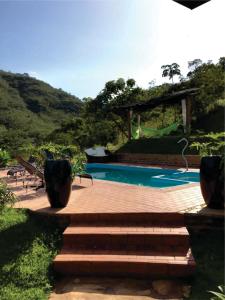 a swimming pool with a wooden deck and stairs next to avisor at Acqualume Cachoeiras in Delfinópolis