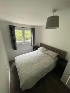 a bedroom with a white bed and a window at 1-Bedroom Chalet at Maryville Caravan Site - Uddingston, Glasgow in Uddingston