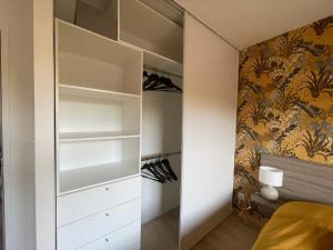 sypialnia z garderobą z białymi szafkami w obiekcie Appartement Les Jardins de Jules Verne - Côté Jardin w Amiens