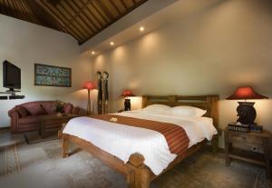a bedroom with a large bed and a couch at Ajanta Villa in Sanur