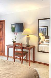 een slaapkamer met een bureau met een lamp en een bed bij Beachfront Hotel Tramonto in Jacó