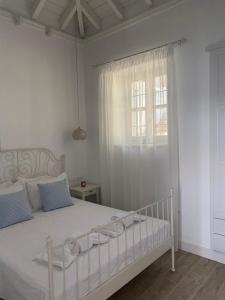 a bedroom with a white bed with blue pillows and a window at Halki Sea Breeze - a waterfront villa in Halki