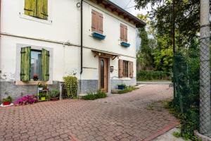 an old white house with a brick driveway at Appartamento Al Vigneto in Montorio Veronese