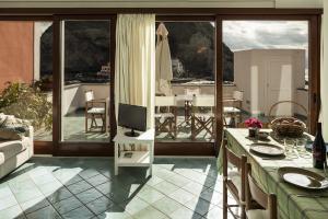 ein Wohnzimmer mit einem TV und einem Tisch mit Stühlen in der Unterkunft Appartamenti Le Pleiadi - Sant'Angelo D'Ischia in Ischia