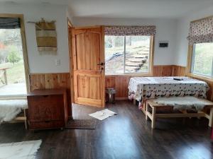 a room with two beds and a table and a window at Cabaña Turismo EL SUSURRO in Coihaique