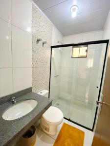 a bathroom with a shower and a toilet and a sink at Hotel Alexânia in Alexânia