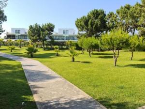 a path in a park with trees and a building at SolTroia - Casa do Pinheiro in Troia