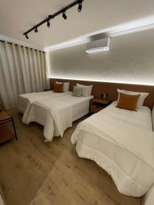 two beds in a hotel room with white sheets at Casa Bem Vino in Bento Gonçalves