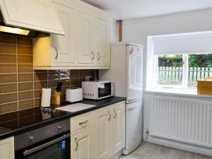 a kitchen with white cabinets and a white refrigerator at The East Wing At Grove Hall in Bodfari