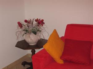 un vaso di fiori su un tavolo accanto a un divano rosso di La Casetta Arancione appartamento a Stroncone