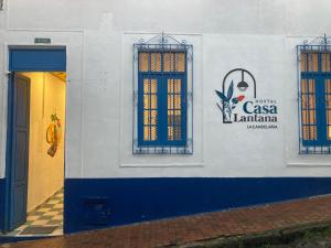 a white building with two windows and a door at Hostal Casa Lantana La Candelaria in Bogotá
