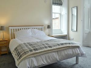 a bedroom with a bed with white sheets and a window at Halleaths Home Farm in Lochmaben
