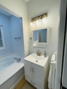 La salle de bains blanche est pourvue d'un lavabo et d'une baignoire. dans l'établissement Modern PGA Village Mets Spring Training Condo A, à Carlton