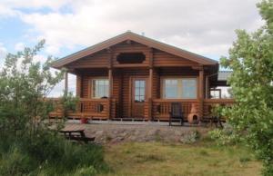 a large wooden cabin with benches in front of it at Log Cabin at White River in Kiðjaberg