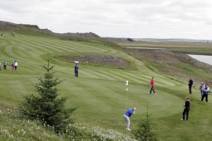 a group of people playing golf on a golf course at Log Cabin at White River in Kiðjaberg