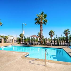 una piscina con palmeras en un complejo en Homestay Suites - Studios & Spas, en Moreno Valley