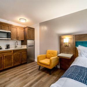 1 dormitorio con 1 cama y 1 silla y cocina en Homestay Suites - Studios & Spas, en Moreno Valley