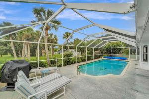 a patio with a pool and chairs and a pergola at Tropical Oasis in Port Charlotte