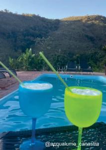 德爾菲諾波利斯的住宿－Acqualume Cachoeiras，坐在游泳池畔的桌子上享用2杯鸡尾酒