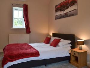 a bedroom with a bed with a red blanket on it at Mill Force Cottage in Bowes