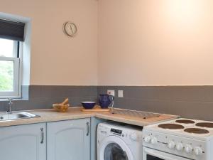 a kitchen with a stove and a washing machine at Mill Force Cottage in Bowes
