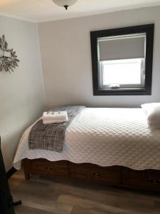 a white bedroom with a bed with a window at Alma’s Cape Shore Cottage! Your home away from home! in Bonavista