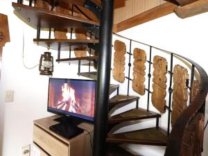 Telewizor siedzący na stojaku obok spiralnych schodów w obiekcie Chalet Rosa w Reith im Alpbachtal