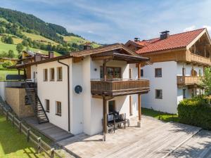 ein großes weißes Haus mit einer Holzterrasse in der Unterkunft Haus Bergblick in Westendorf