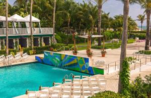 a beach with a pool, chairs, and a pool table at Kimpton Surfcomber Hotel, an IHG Hotel in Miami Beach