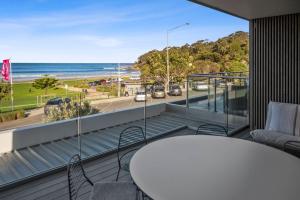 een balkon met een tafel en stoelen en uitzicht op het strand bij Louttit Bay Apartment 1 in Lorne