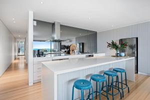 een keuken met een wit aanrecht en blauwe krukken bij Louttit Bay Apartment 1 in Lorne