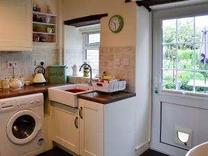 a kitchen with a sink and a washing machine at The Bellringers Cottage in Llandegla