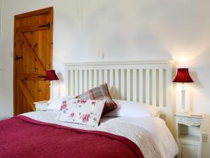 a bedroom with a bed with red sheets and two lamps at The Bellringers Cottage in Llandegla