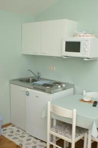 eine weiße Küche mit Spüle und Mikrowelle in der Unterkunft Studio Vodice 4172a in Vodice