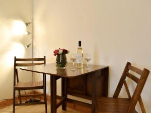 una mesa con dos copas y una botella de vino en Spey Cottage, en Aberlour