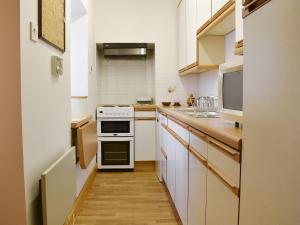 a kitchen with white cabinets and a stove top oven at Spey Cottage in Aberlour