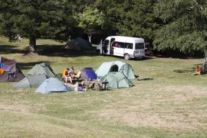 eine Gruppe von Menschen, die auf einem Feld mit Zelten sitzen in der Unterkunft Rotorua Thermal Holiday Park in Rotorua