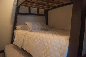 Una cama con sábanas blancas y almohadas en un dormitorio en Apartamento privado a 2kms del parque del café, en Montenegro