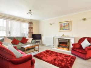 uma sala de estar com mobiliário vermelho e uma lareira em Westburn em Comrie