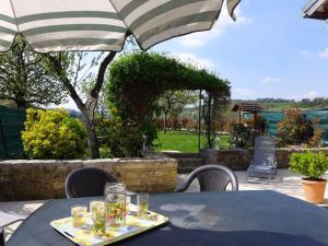un tavolo con vassoio di bicchieri e un ombrello di Charmant gîte familial avec terrasse, garage et jardin clos à Pont-la-Ville - FR-1-611-35 a Pont-la-Ville