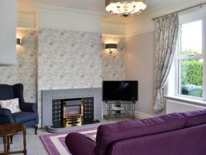 a living room with a purple couch and a fireplace at Glenfield in Keighley