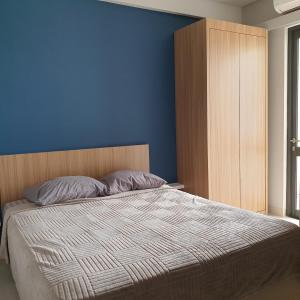 a bedroom with a bed and a blue wall at CozyHomes at One Residence Batam in Batam Center