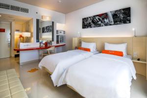a bedroom with two beds and a desk in it at HARRIS Hotel and Conventions Denpasar Bali in Denpasar