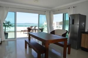 a kitchen with a table and chairs and a refrigerator at Belíssima cobertura duplex - De frente para o mar - Bombinhas-SC in Bombinhas