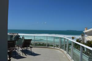 Un balcón con sillas y vistas al océano. en Belíssima cobertura duplex - De frente para o mar - Bombinhas-SC, en Bombinhas