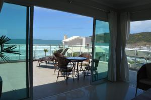 balcón con mesa, sillas y vistas al océano en Belíssima cobertura duplex - De frente para o mar - Bombinhas-SC, en Bombinhas