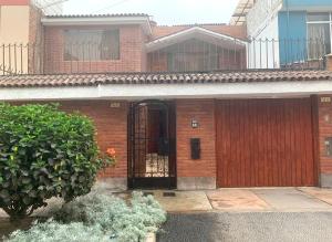 una casa de ladrillo con una puerta delante de ella en Hermoso dpto amoblado, wifi, terraza,cochera pequeña y en San Miguel, en Lima