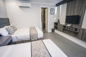 Habitación de hotel con 2 camas y TV de pantalla plana. en Anika Suites, en Cebú