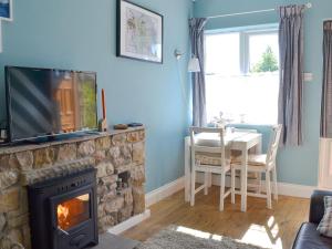 a living room with a fireplace with a television and a table at Crown Courtyard Cottage in Grewelthorpe